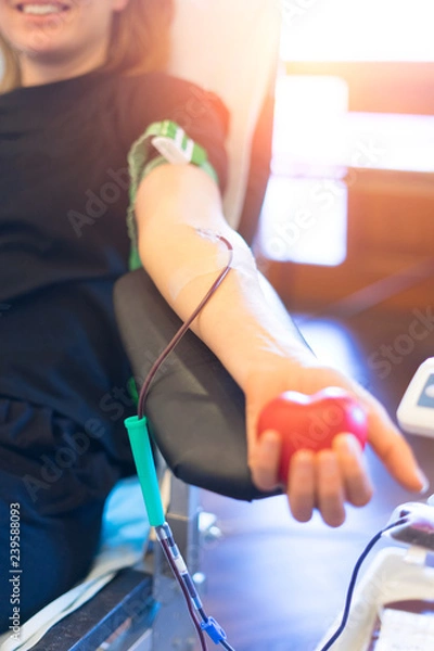 Fototapeta young woman as blood donor at donation with a bouncy ball holding in hand