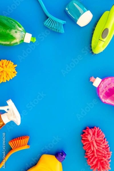Fototapeta Housecleaning with detergents, soap, cleaners and brush in plastic bottles on blue background top view mockup