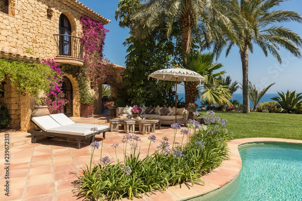 Fototapeta Luxurious summer or rest home with comfortable sofa and cushions in front of the pool with a lovely garden