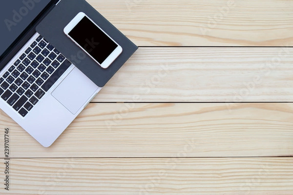 Fototapeta Wood office desk table with laptop open screen, smartphone, and notebook. Top view with copy space, flat lay show device and equipment.