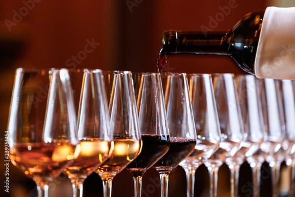 Fototapeta Wine glasses in a row. Pouring wine. Buffet table celebration of wine tasting. Nightlife, celebration and entertainment concept