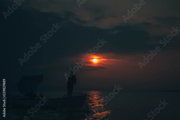 Fototapeta Fisherman collects fish in sunset