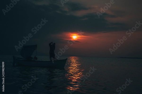 Obraz Fisherman tries to collect fishes in sunset