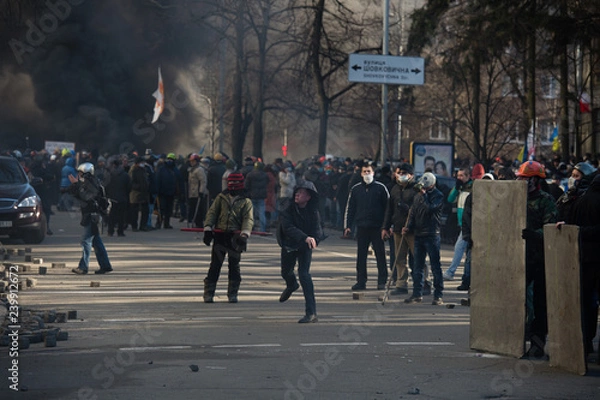 Obraz Riots, fire in the city, protester throws a stone