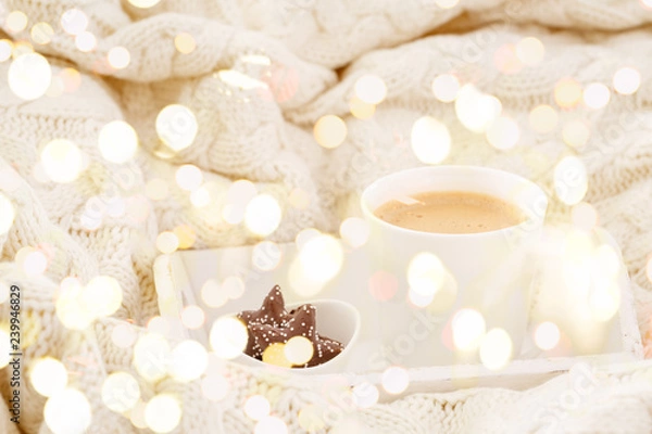 Fototapeta Hot beverage mug with chocolate cookies in a white wool blanket. Hot drink, cozy home and cold season concept