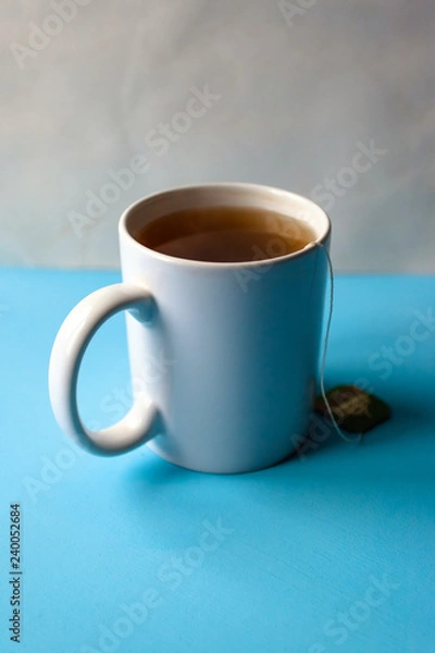 Fototapeta mug with tea in a bag on a blue table