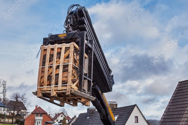 Obraz Eine Palette Kaminholz schwebt in der Luft an einem Kran