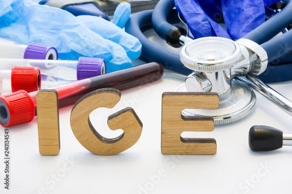 Fototapeta Medical abbreviation IGE in laboratory diagnostics. Letters, create words IGM, meaning Immunoglobulin E antibody, are surrounded by test tubes with blood, stethoscope and other medical equipment