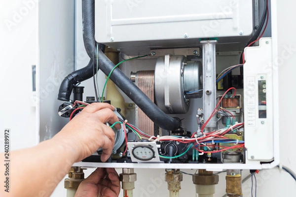 Obraz worker set up central gas heating boiler at home