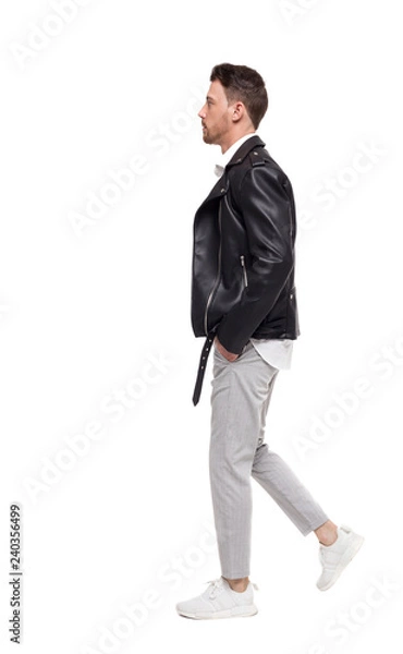 Fototapeta Side view of going  handsome man in a leather jacket and trouser