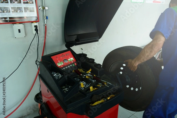 Obraz the green digital number on the panel of red tyre balancing machine and the mechanic install the wheel before test
