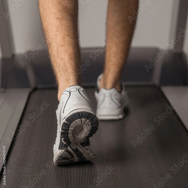 Obraz The legs of man running on treadmill in the gym. Health and sport concept. Healthy lifestyles