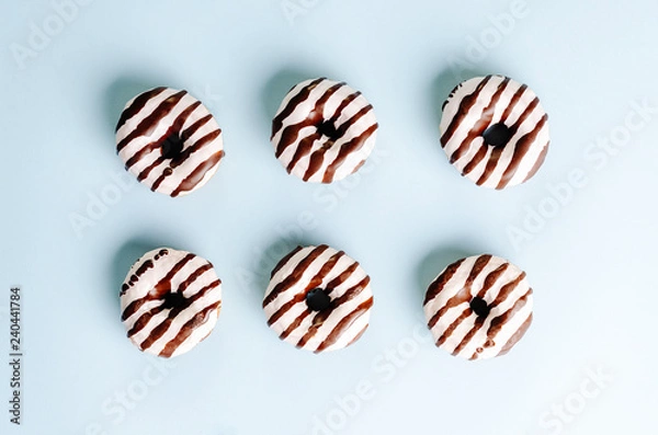 Fototapeta Donuts wit white and dark chocolate on top on a blue background. Top view. Flat lay.