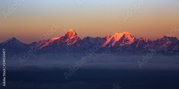 Fototapeta Mountain Range Sunrise, mountains glowing in the sunshine at dawn. Snow covered mountain peaks in the distance, panoramic view. Purple, Orange atmosphere. Sichuan Province China. Rugged wilderness