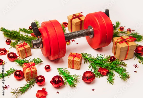 Obraz Christmas or New Year on a white background. Composition with dumbbells, gift, red and gold glass balls, fir tree branches for healthy lifestyle and sport