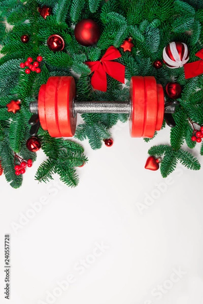 Obraz Christmas or New Year on a white background. Composition with dumbbells, gift, red and gold glass balls, fir tree branches for healthy lifestyle and sport