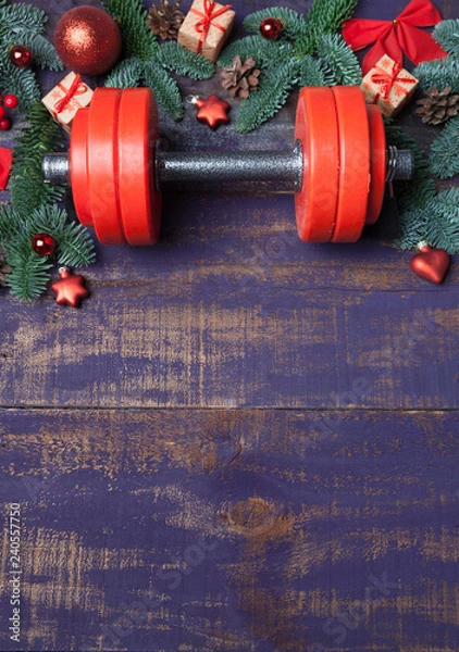 Obraz Christmas or New Year on a violet wooden background. Composition with dumbbells, gift, red and gold glass balls, fir tree branches for healthy lifestyle and sport