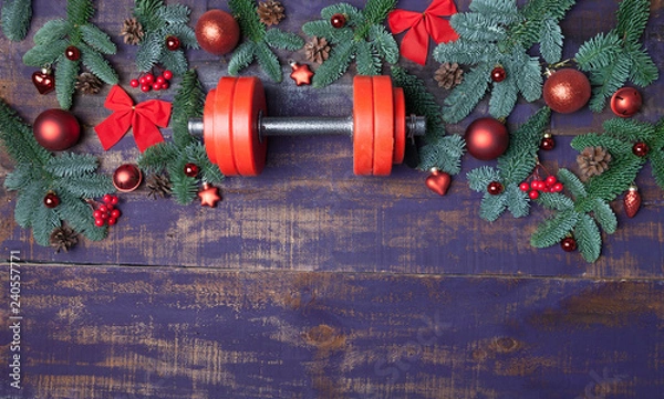 Obraz Christmas or New Year on a violet wooden background. Composition with dumbbells, gift, red and gold glass balls, fir tree branches for healthy lifestyle and sport