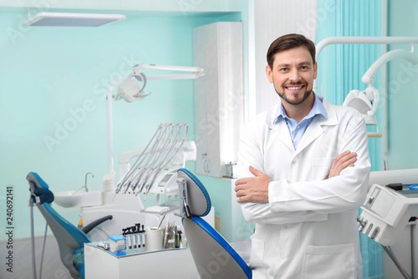 Obraz Fachowy męski dentysta w białym żakiecie w miejscu pracy. Miejsce na tekst
