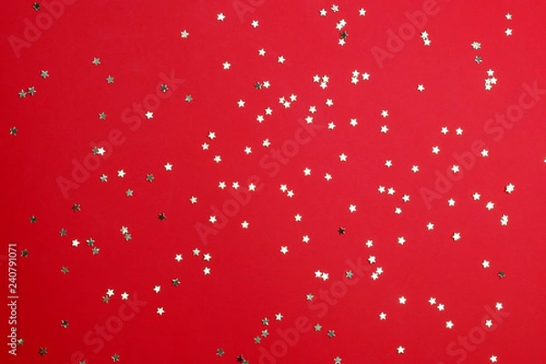 Obraz Star-shaped confetti on red background.