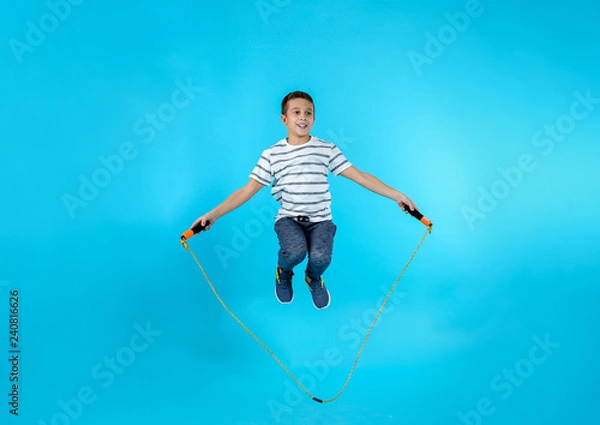 Fototapeta Full length portrait of boy jumping rope on color background
