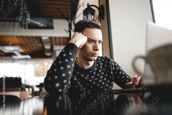 Fototapeta A freelancer or journalist frowns at a laptop. Has difficulty completing a job or order