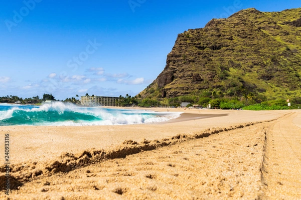 Fototapeta Sunny day at Makaha beach on the west side of the island of Oahu in Hawaii amidst beautiful green mountains with volcanic formation in front of the blue sea