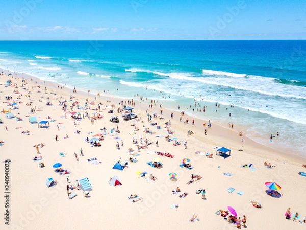 Fototapeta An aerial view of people on the beach with blue water on hot summer's day