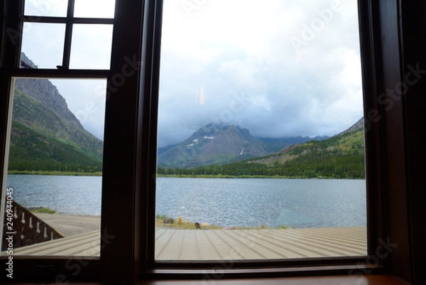 Fototapeta Looking through a window frame at a clear blue lake in Glacier National Park.