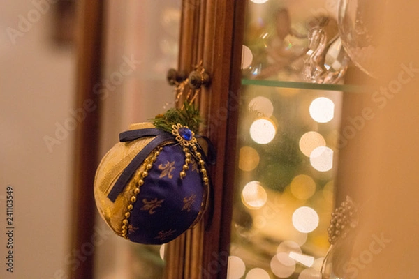Fototapeta horizontal image with a close-up detail of a Christmas ball re-issued in blue and gold-colored fabric hanging from a knob