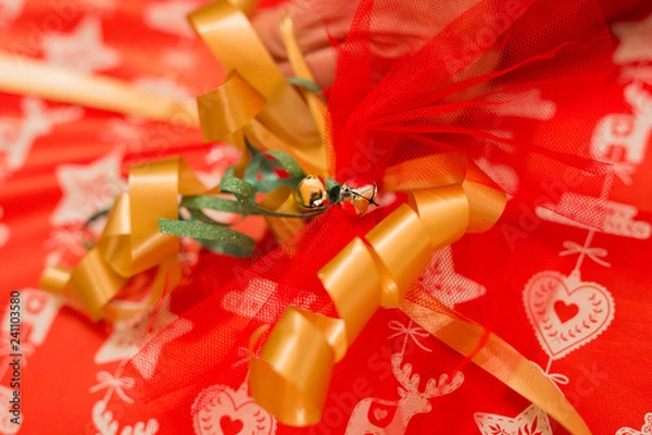 Fototapeta horizontal image with a close-up detail of a golden little bell used to decorate a Christmas package