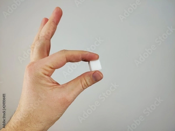 Fototapeta hand holding sugar cube between finger tips