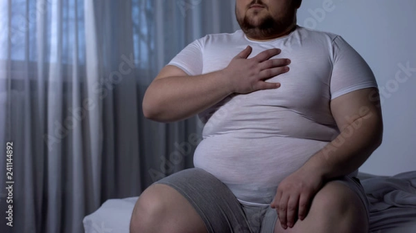 Fototapeta Otyły mężczyzna cierpiący na ból w klatce piersiowej, wysokie ciśnienie krwi, poziom cholesterolu