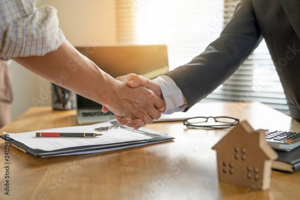 Fototapeta Banker business man shaking hands with client and sign contrac document for comfirm corporation or finished loan agreement for house or building property.Document in photo is fake only for stock photo