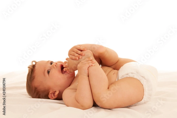 Fototapeta Hapy baby boy in playing on bed isolated over white