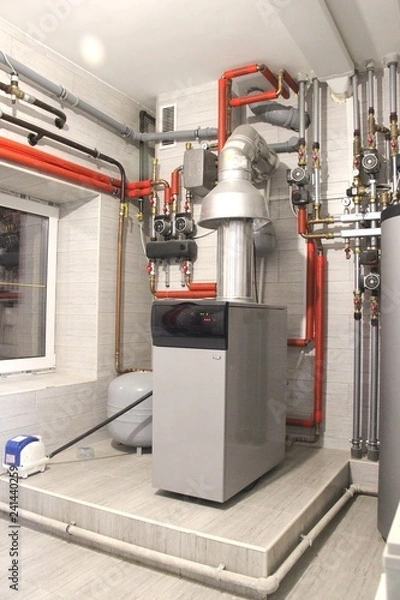 Obraz Heating of the house with a large number of steel pipes, pressure gauges and metal pipes, selective focus. Boiler and pipes of the heating system of the house.