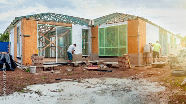 Fototapeta Housing construction with bricklayers and tradies working on house in Australia