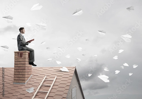 Fototapeta Man on brick roof reading book and paper planes flying in air