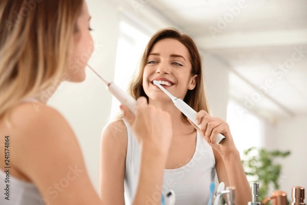 Fototapeta Young beautiful woman with toothbrush near mirror in bathroom. Personal hygiene