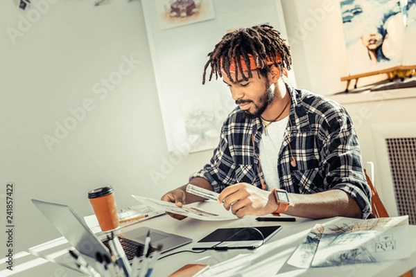 Fototapeta Bearded interior designer with dreadlocks holding ruler in his hand