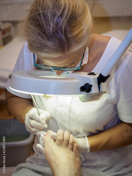 Obraz Female chiropodist working on a senior clients feet.