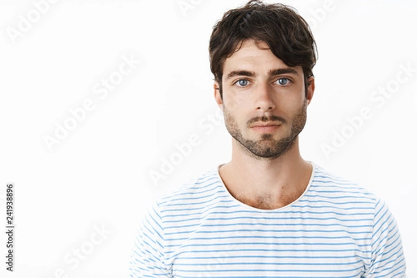 Fototapeta Authentic shot of young attractive guy with slight rash on neck after shaving looking strict and serious at camera with no emotions being chill and confident staring at camera with deep blue eyes