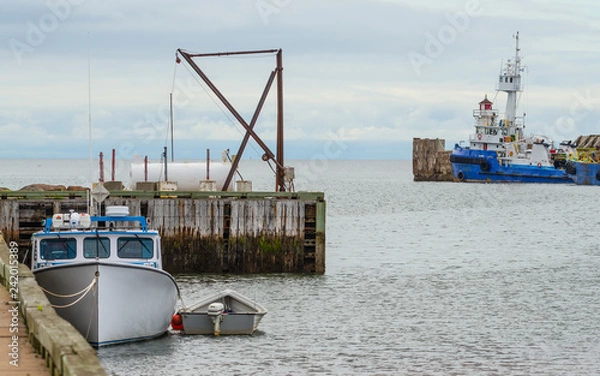 Fototapeta Boats docked and idle for the day, no people around, hot summer day on a wharf in a New Brunswick harbour.