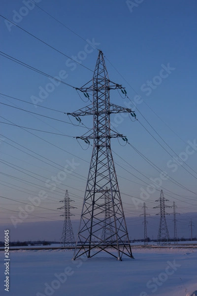 Fototapeta Power lines in winter. Poles of power lines on the background of a winter sky. Copy space.