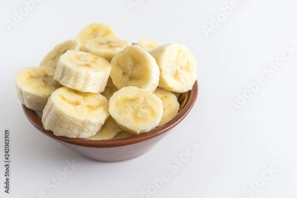 Fototapeta Bowl with banana slices on white background