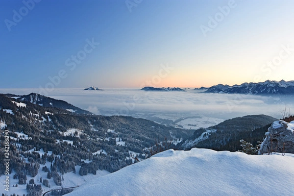 Obraz Beautiful morning mood in the Allgaeu Alps at a cold winter day. Snow-covered alpine landscape with mountains sticking out of a cloud layer and red glowing horizon before sunrise (Bavaria, Germany).