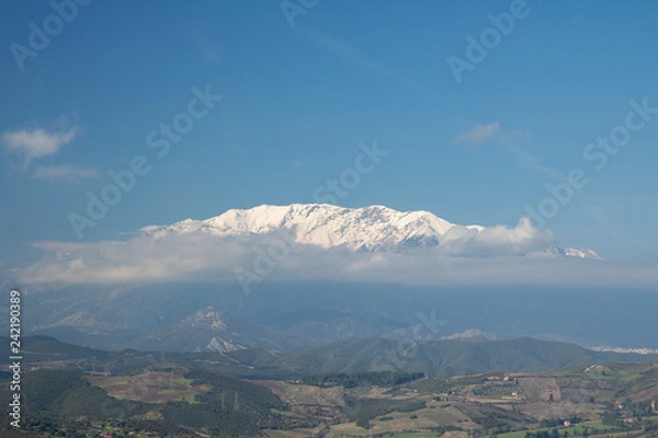 Obraz snowed mountain top appearing through the clouds