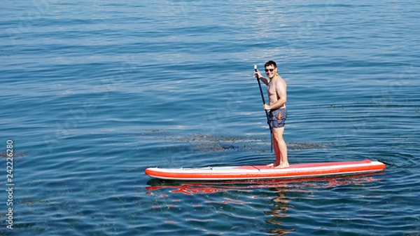 Obraz Friendly young man active with paddel-board on Lake Constance