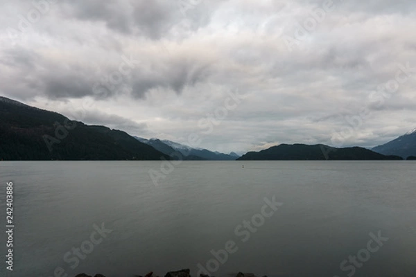 Obraz morning on beautiful Harrison lake with mountain background and cloudy sky.