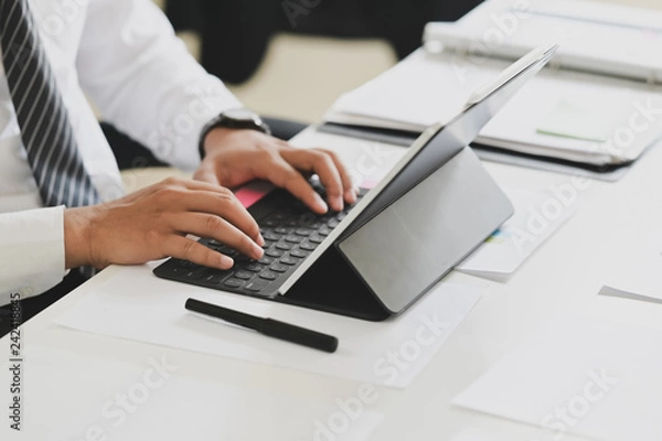 Fototapeta Business man working on tablet computer on white desk in office
